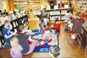  ?? (NWA Democrat-Gazette/Susan Holland) ?? Children and some parents listen Oct. 21 as library assistant Brittany Mangold reads the book “Moongame” during a story time as part of the Moon Over Main Street event.