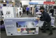  ?? CHARLIE RIEDEL — THE ASSOCIATED PRESS FILE ?? In this file photo, Jesus Reyes pushes a television down an aisle as he shops at a Best Buy store in Overland Park, Kan. Just before the Super Bowl, retailers normally discount their selections of HDTVs and other home-theater essentials making January...