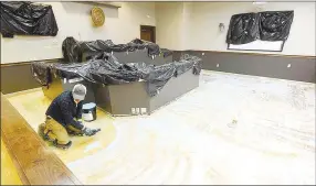  ?? NWA Democrat-Gazette/FLIP PUTTHOFF ?? Sam Bouphasiri spreads glue on the floor of a courtroom at the Benton County Courthouse annex to prepare it for carpet.