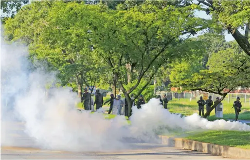  ?? AP ?? Venezuelan Bolivarian National Guard officers fire teargas towards a resident who tries to walk to the Paramacay military base in Valencia, Venezuela. Venezuelan ruling party chief Diosdado Cabello said the military squashed a terrorist attack at the...