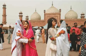  ?? AFP ?? Muslim women exchange Eid greetings on the occasion of Eid Al Fitr at the Badshahi Mosque in Lahore yesterday.