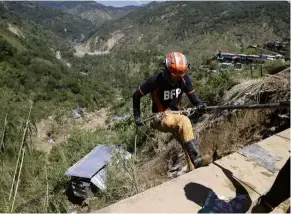  ?? — AP ?? Search underway: A rescue worker rappelling down to an area where victims are believed to have been buried by a landslide in Itogon.