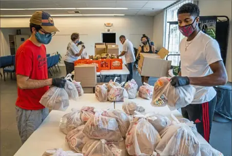  ?? Andrew Rush/ Post- Gazette ?? From left, Will Emanuel and Will Taylor, of Bible Center Church in Homewood, package breakfast and lunch for the church’s meal distributi­on program on Aug. 21. The church will distribute the food as part of its program to deliver lunches to children in need.