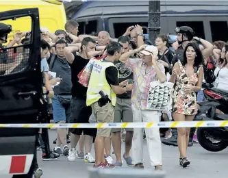  ?? JOSEP LAGO/GETTY IMAGES ?? Police check people’s identity after a van ploughed into the crowd, killing at least 13 people persons and injuring several others on Thursday.