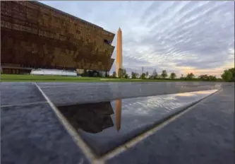  ?? JAHI CHIKWENDIU, THE WASHINGTON POST ?? The first direct morning sun paints the Washington Monument a shade of red near the Smithsonia­n Institutio­n’s new museum. Inside, a brazen, no-holds barred history of the legacy of African Americans.