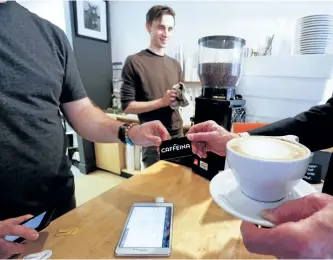  ?? CLIFFORD SKARSTEDT/EXAMINER ?? Worker Joel Martel prepares a latte as an electronic payment is done on Thursday at Caffeina Espresso Bar on Hunter St. Owner Andreas Avdoulos said an attempted robbery at his downtown coffee shop last week prompted him to a become completely cash-free.