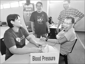  ??  ?? Dr Sim (seated, right) gets his blood pressure checked, as (standing, from left) Kho and Bong look on. — Photo by Muhammad Rais Sanusi
