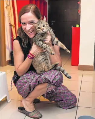  ?? Antonie Robertson / The National ?? Sulafa Tower resident Carla Julian saw firefighte­rs bring birds, dogs and cats to safety. She was at home when the fire started and quickly took her cat, Miss Bradshaw, outside.