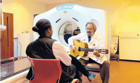  ??  ?? Andrew Rossetti, a licensed music therapist, uses guitar music and visualizat­ion exercises to help calm patients.