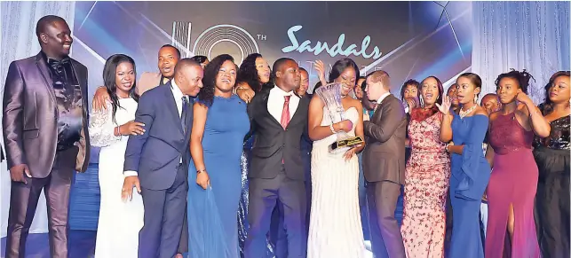  ??  ?? The 2017 Sandals Ultimate Award winner, Jardine Vassell (centre holding trophy), of Beaches Ocho Rios, is flanked by her colleague competitor­s from across the Caribbean and deputy chairman of Sandals Adam Stewart during the award ceremony last Thursday...