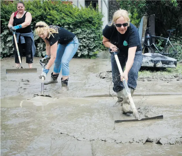  ?? TIJANA MARTIN/ CALGARY HERALD ?? Carre Regnier, left, Kim Caputo and Judi Vandenbrin­k help with the cleanup in the flood-damaged Bowness area of Calgary on Monday.