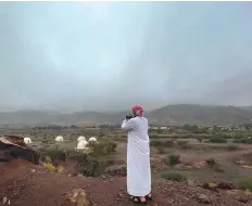  ?? Ahmed Ramzan/Gulf News ?? A resident captures the transforme­d horizon on his mobile phone camera in Hatta.