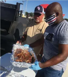  ?? (Special to The Commercial/ Deborah Horn) ?? Jim Hudgins (left) of Memphis and former Pine Bluff firefighte­r Laron Edwards of Bentonvill­e, who was a close friend of slain police officer Kevin Collins, help prepare food for family and friends on Saturday in honor of Collins.
