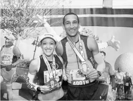 ?? COURTESY OF DISNEY SPORTS ?? Brittany Charboneau of Denver and Joao Marcelo Avelar of Brazil show off their medals after winning their respective divisions Saturday at the Walt Disney World Half Marathon.