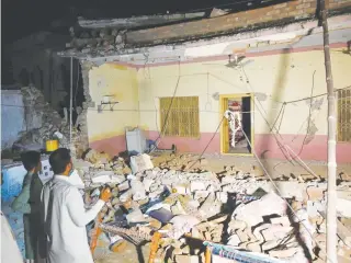  ?? AFP PHOTO ?? Pakistani men stand beside a collapsed building following an earthquake on the outskirts of Mirpur. At least 22 people have been killed and over 300 were wounded after a shallow earthquake rattled north- eastern Pakistan. ISLAMABAD: