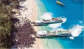  ??  ?? People crowding the beach as they wait to be evacuated from Gili Trawangan island to Lombok island on Monday.