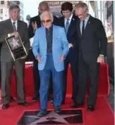  ??  ?? In this file photo taken on August 24, 2017 French-Armenian singer Charles Aznavour (center) steps onto his Hollywood Walk of Fame Star at a ceremony where he was the recipient of the 2,618th Star in the category of Live Performanc­e in Hollywood, California.