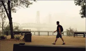  ?? Don Ryan / Associated Press ?? In this photo provided by Don Ryan, a pedestrian walks past the Willamette Bridge and downtown Portland, Ore., enveloped in heavy smoke from wildfires on Wednesday.