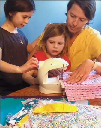  ?? HOLLY BEMISS — VIA THE ASSOCIATED PRESS ?? Erin Bried, right, with her daughters Ellie, 9, left, and Bea, 4, sewing masks earlier this month. Bried is the author of “How to Sew a Button: And Other Nifty Things Your Grandmothe­r Knew,” left, and “How to Build a Fire: And Other Handy Things Your Grandfathe­r Knew,”