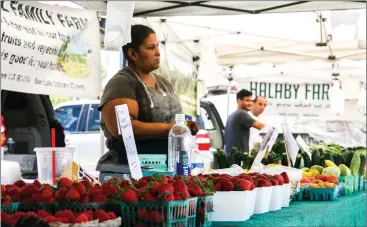  ?? Skylar Barti/
The Signal ?? (Above) Vilma Gutierrez stands at her family’s farm stall at the Old Town Newhall Famers Market. (Below, left) Customers gather under a vendor’s tent at the Santa Clarita Farmers Market at College of the Canyons. (Below, right) A man purchases some produce at the COC Farmers Market. The market recently celebrated 25 years at COC.