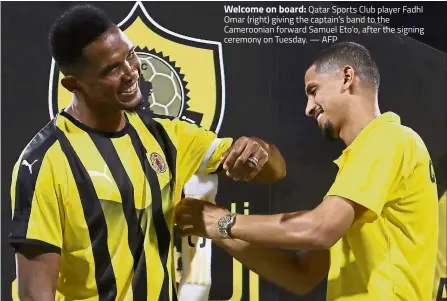  ?? — AFP ?? Welcome on board: Qatar Sports Club player Fadhl Omar (right) giving the captain’s band to the Cameroonia­n forward Samuel Eto’o, after the signing ceremony on Tuesday.