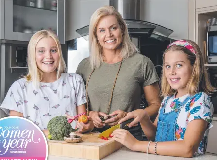  ?? Picture: JERAD WILLIAMS ?? Gold Coast Women of the Year Wellness Warrior nominee and former Ironwoman world champ Karla Gilbert prepares a meal with daughters Ella James, 12, and Summer James, 9.