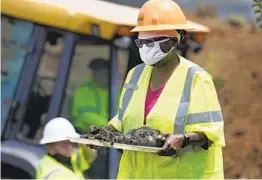  ?? MIKE SIMONS AP ?? Forensic anthropolo­gist Phoebe Stubblefie­ld carries a tray of items found at Oaklawn Cemetery during a test excavation for possible mass graves.