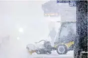  ??  ?? A worker tries to clear snow and ice from the Metro Government Center Plaza station as the snow picked up in downtown Minneapoli­s