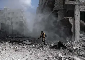  ?? AFP / Getty Images ?? A civil Defence volunteer, known as the White Helmets, checks the site of a regime air strike in the rebelheld town of Saqba, in the besieged Eastern Ghouta region on the outskirts of Damascus.