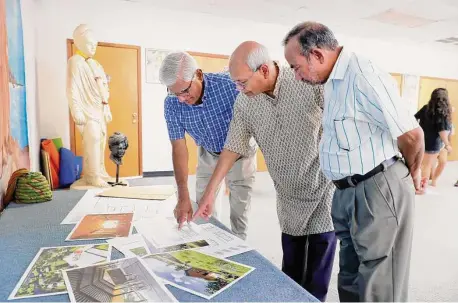  ?? Photos by Michael Wyke / Contributo­r ?? Ashok Danda, left, Subash Gupta, middle, and Baru Goyal, right, look over artist concepts for the Hindu Heritage Youth Camp.