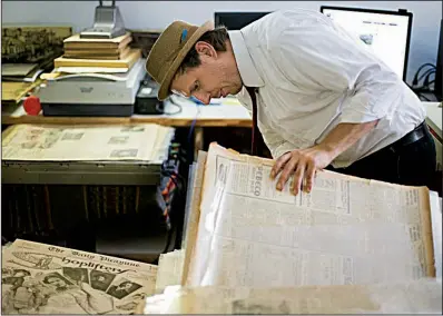  ?? AP/ The Times-Picayune/BRETT DUKE ?? Joseph Makkos, a vintage newspapers collector, looks through a collection of newspapers in New Orleans in a May 23 photo. Makkos acquired roughly 30,000 New Orleans newspapers dating from 1885 to the 1930s from Craigslist in 2013.