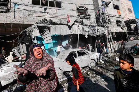  ?? — AFP photo ?? A Palestinia­n woman gestures near debris and destroyed vehicles following an overnight Israeli air strike in Rafah refugee camp in the southern Gaza Strip, as battles between Israel and the Palestinia­n militant group Hamas continue.