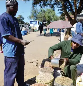  ??  ?? Mr Zuvarashe Makarati (right) prepares a 20 litre pail of peanuts he is selling for $8 to a client at Shasha Market near Renkini bus terminus last week. Picture by Dennis Mudzamiri