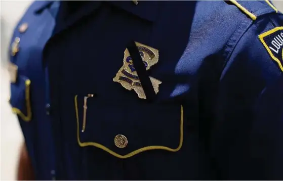  ?? Joshua Lott / Getty Images ?? A black band is displayed around Louisiana State Police officer Bryan Lee’s badge during a prayer vigil for Baton Rouge Police officers Montrell Jackson and Matthew Gerald and East Baton Rouge Parish Sheriff Deputy Brad Garafola.