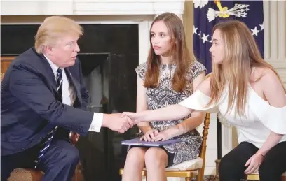  ?? — AFP ?? President Donald Trump shakes hands with Marjory Stoneman Douglas High School student Ariana Klein watched by fellow student Carson Abt at the start of a “listening session” on gun violence with teachers and students in the State Dining Room of the...