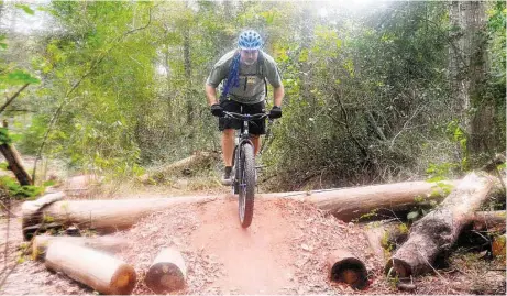  ?? David Hopper ?? Scott Moran of Cypress jumps an obstacle at the 100 Acre Wood Preserve. Precinct 4 recently opened a one-mile, asphalt trail on the eastern side of the park. The trail extends from the YMCA facility at Texas 249 to the Cypresswoo­d Hike and Bike Trail...