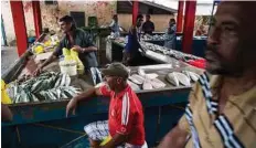  ??  ?? Workers cut and sell seafood at a fish market.