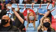  ??  ?? Fans of Man City wear protective face masks in the stands prior to the League Cup final between City and Tottenham at Wembley on April 25