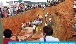  ?? — AFP ?? HPAKANT: Volunteers bury bodies of miners in a mass grave while relatives look on during a funeral ceremony near Hpakant in Kachin state.