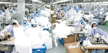  ?? — AFP file photo ?? Photo shows workers producing protective clothing at a factory which previously produced suits and sportswear and switched production for the fight against the deadly coronaviru­s, in Wuxi in China’s eastern Jiangsu province.