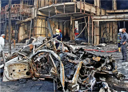  ??  ?? Devastatio­n: The mangled wreckage of the IS truck bomb smoulders outside the Baghdad shopping mall it destroyed yesterday