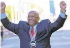  ??  ?? Mayor Bernard C. “Jack” Young raises his hands as he jokes with photograph­ers and crosses the finish line of the Baltimore Marathon wearing a medal.