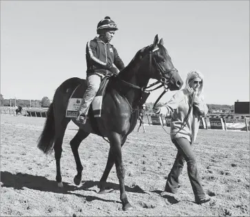  ?? Julie Jacobson Associated Press ?? EXAGGERATO­R, with exercise rider Jermal Landry, is led to the main track by assistant trainer Julie Clark.