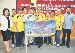  ??  ?? TAHNIAH: Emang (tiga kiri), Isak (lima kanan) dan pendaki Ekspedisi Menawan Gunung Kinabalu menunjukka­n cakera padat (CD) mengandung­i rakaman pengalaman mereka.