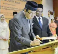  ??  ?? Sultan Sharafuddi­n signing a plaque to officiate the Shah Alam Hospital as Subramania­m looks on at the hospital yesterday.