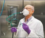  ?? (AP/Allen G. Breed) ?? Researcher William Bennett tilts his head back to test the fit of a mask inside a sealed chamber in a lab at the University of North Carolina in Chapel Hill, N.C. Working with Dr. Philip Clapp, Bennett tested several different masks collected by the AP.