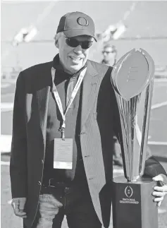  ?? JAYNE KAMIN- ONCEA, USA TODAY SPORTS ?? Nike’s Phil Knight, a major booster for Oregon athletics, poses with the College Football Playoff trophy last Jan. 1.