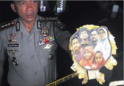  ?? Nanda Andrianta ?? The Associated Press Surabaya Police Chief Col. Rudi Setiawan shows a picture of the family of Dita Oepriarto. The family carried out suicide bombings at three churches on Sunday in Surabaya, Indonesia.