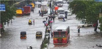  ??  ?? ■ Above: Vehicles ply on a waterlogge­d street at Kurla during monsoon rains in Mumbai yesterday.