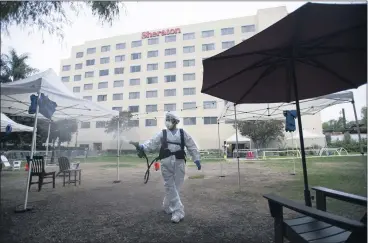  ?? COURTESY OF LOS ANGELES COUNTY ?? ISD employee Florida Hernandez sprays disinfecta­nt on Oct. 23 in outdoor common areas for patients staying at the Pomona Fairplex Medical Shelter. It is one of four COVID-19 medical shelters operating in Los Angeles County.